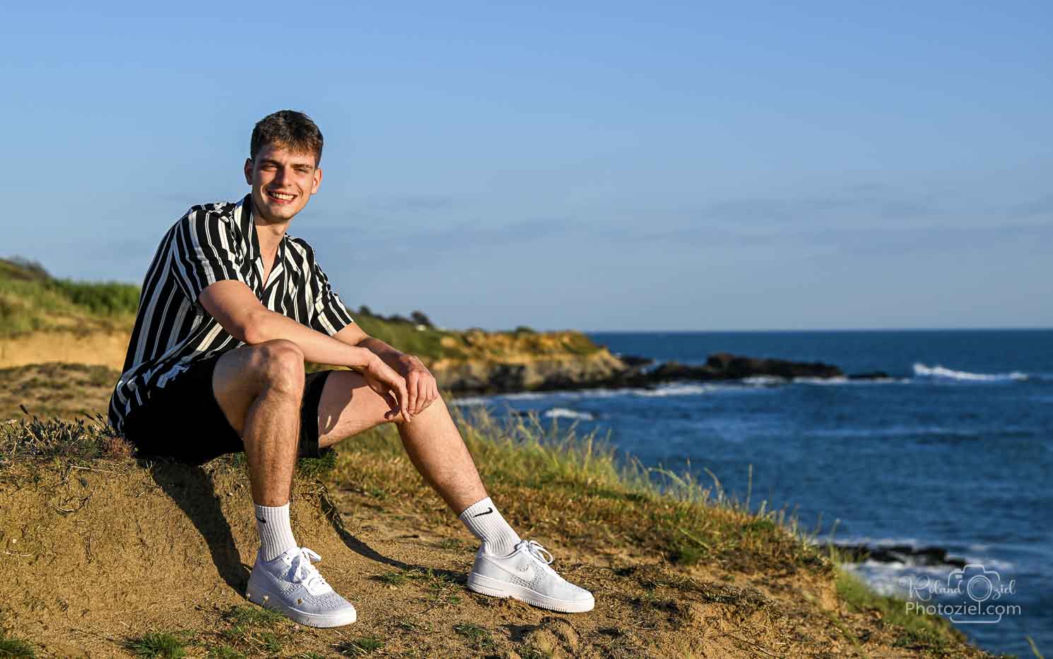 Photo d&apos;un jeune souriant avec en fond le bord de mer