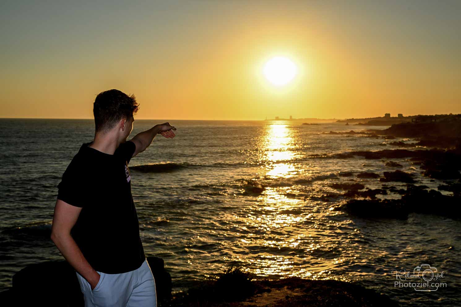 Photo d&apos;un jeune homme qui pointe le doigt vers le soleil couchant