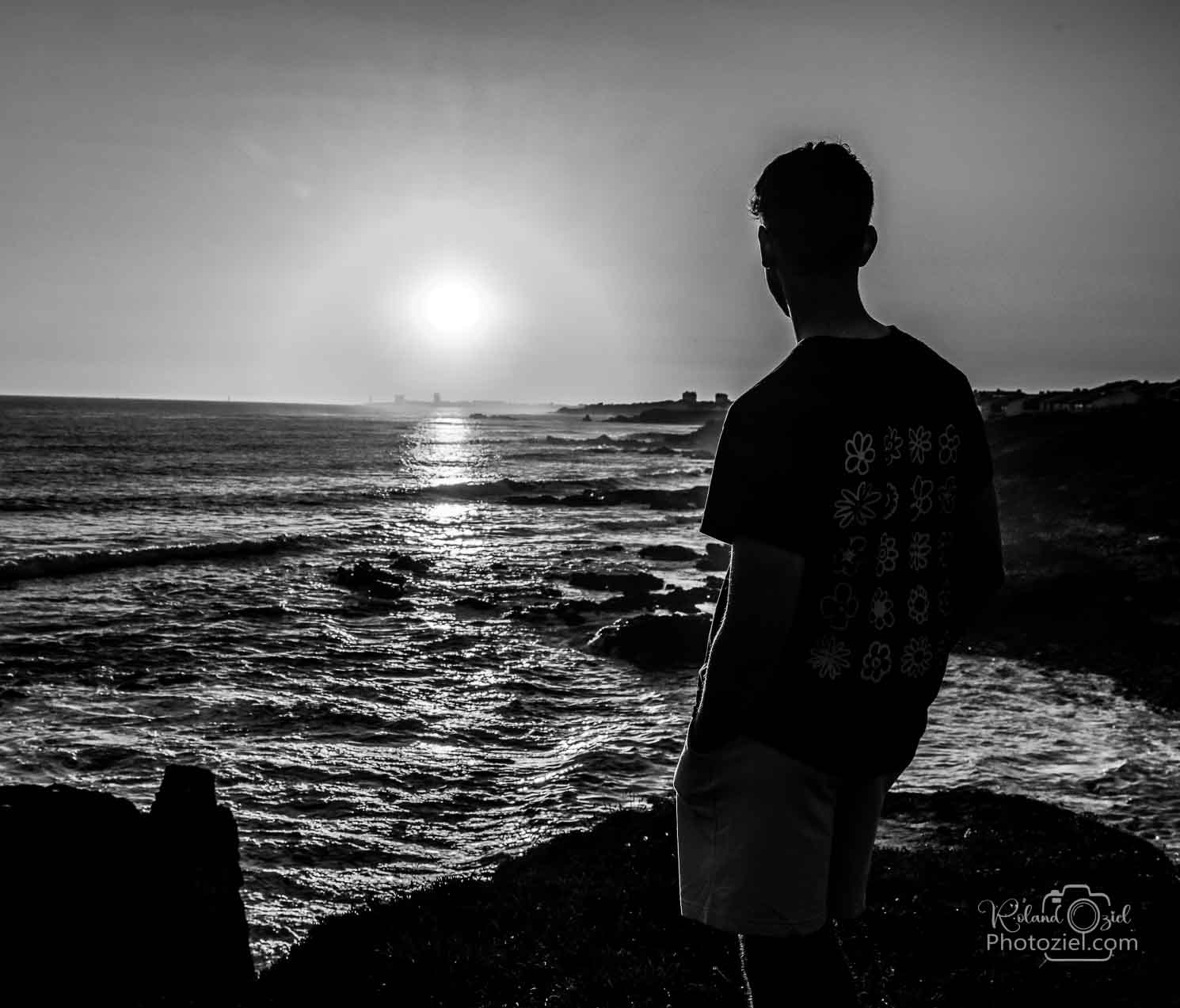 Photo noir et blanc d&apos;un jeune homme le soir au bord de la mer