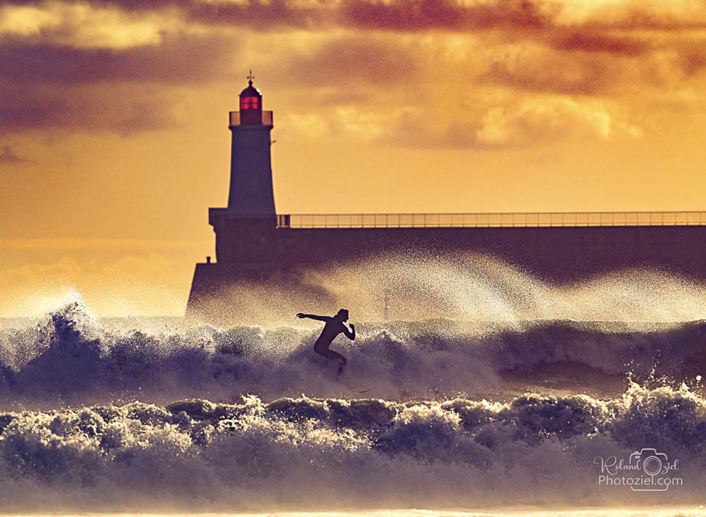 Photo artistique d&apos;un surfeur devant le phare des Sables d&apos;Olonne en Vendée